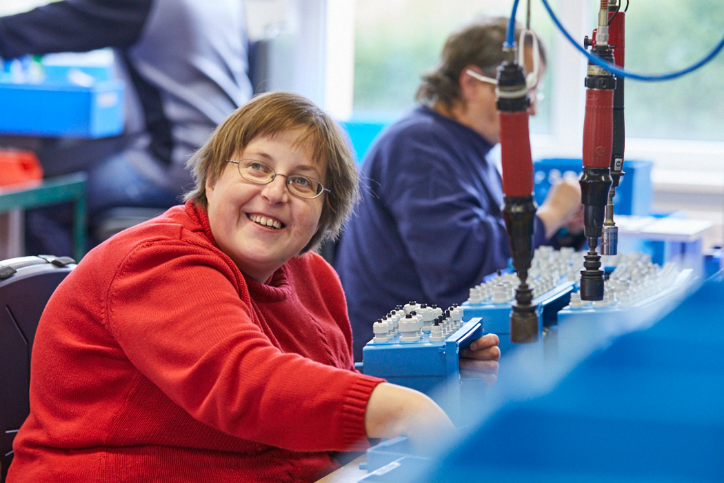 Eine lächelnde Frau arbeitet in der Elektro-Montage