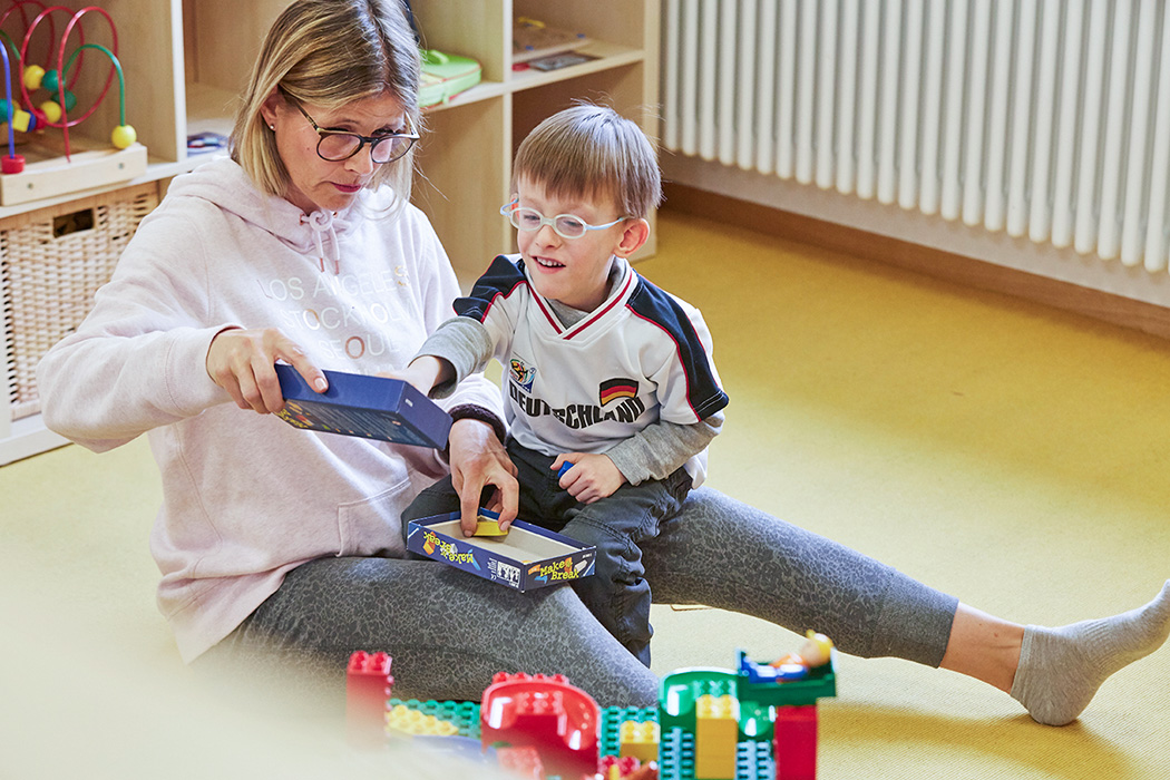 Eine Erzieherin spielt in der Inklusiven Kindertagesstätte mit einem Jungen ein Spiel