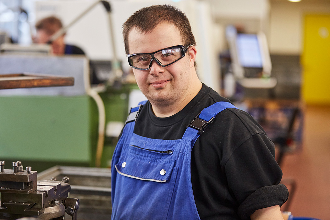 Ein junger Mann mit Arbeitskleidung in der Metallwerkstatt