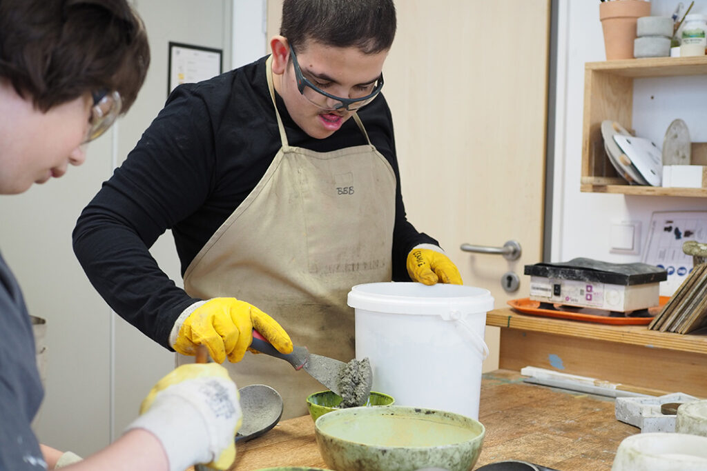 Zwei Menschen gießen Beton in eine Form