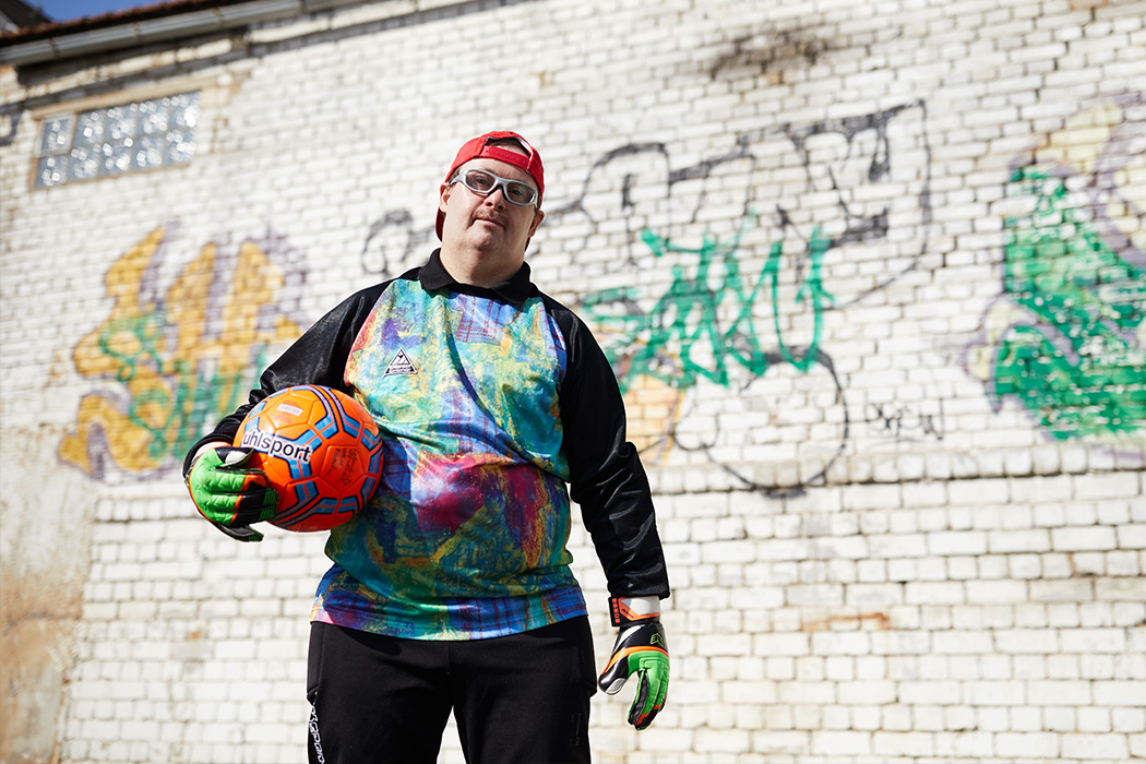 Ein Mann mit Fußball steht auf einem Sportplatz